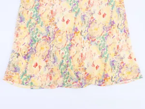 Detailed macro view of the floral print chiffon fabric and wavy hemline of the dress