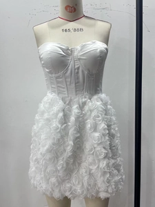 Detail of white strapless corset dress featuring 3D floral applique on the satin skirt