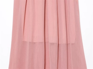 Detail view of double-layered light pink chiffon midi dress hem with sheer fabric texture