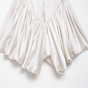 Detailed view of white satin fabric with elegant pleated texture and voluminous folds