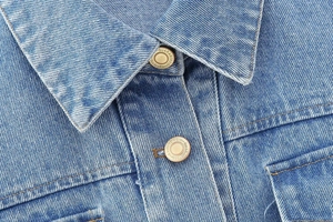 Detailed close-up of denim jacket collar and vintage copper buttons with engraved text