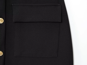 Detail of black woven midi dress with flap pocket and decorative gold embossed buttons