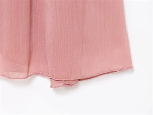 Close-up of pink chiffon midi dress hem with fine vertical texture and rolled edge stitching