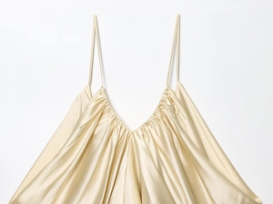 Detail of champagne satin top featuring V-neckline with pleated fabric and thin straps