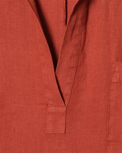 Dettaglio macro dello scollo a V su abito in lino rosso mattone con trama del tessuto