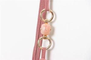 Detail of pink midi dress showing gold metal rings and translucent resin stone on shoulder strap