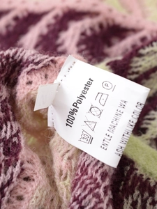 Macro shot of colorful knit fabric showing the 100% polyester care label and size S tag