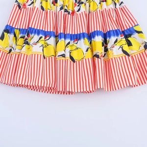 Detail of pleated skirt fabric with yellow lemon print and bold red striped pattern