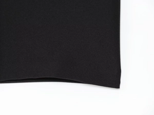 Close-up detail of high-quality black crepe fabric texture and hemline of the midi dress