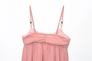 Detail of pink midi dress showing thin straps with gold metal rings and pleated neckline