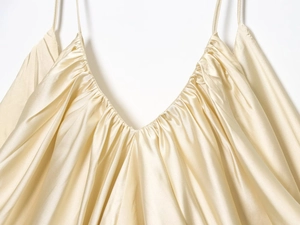 Detailed view of champagne satin fabric with pleated V-neckline and delicate straps