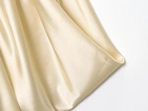 Close-up of champagne gold satin fabric texture showing smooth silk shine and elegant drapes