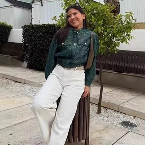 Women's dark green sequined tweed jacket with white wide-leg trousers in outdoor setting