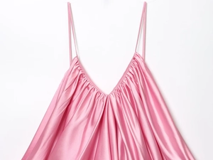 Detail of pink satin camisole featuring delicate pleats and elegant V-neckline texture