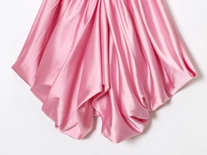 Macro detail of pink satin fabric showing elegant draped pleats and silky texture