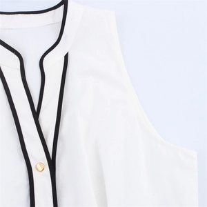 Detail of V-neck white sleeveless blouse with black contrast trim and a gold button