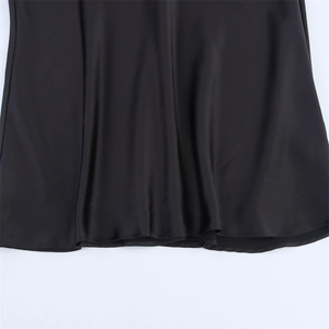 Close-up detail of the glossy black satin dress hem with smooth texture and drape