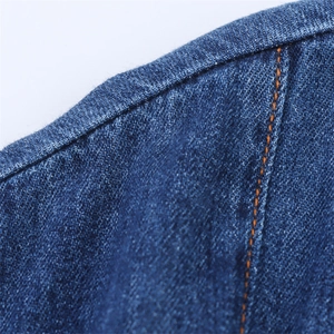 Detail of dark blue denim fabric texture with contrasting orange topstitching seams