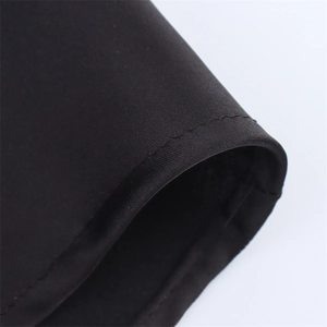 Close-up detail of smooth satin dress hem showing premium stitching and fabric texture