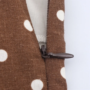 Detailed macro view of the invisible zipper and brown polka dot fabric of the midi dress