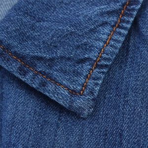 Close-up of blue denim dress featuring orange contrast double stitching and twill texture