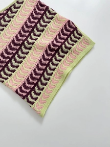 Detailed view of pink and burgundy wave pattern knit fabric on asymmetric shoulder top