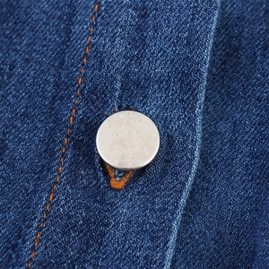 Detail of dark blue denim dress fabric with orange contrast stitching and silver metal button