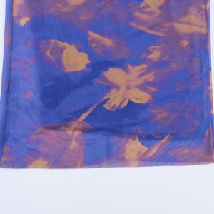 Vue détaillée du tissu en tulle transparent avec motifs floraux bleu et orange vif