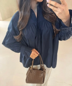 Detail view of the deep blue long-sleeve oversized shirt with pleated ruffles