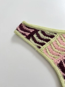 Detail of colorful knit tank top featuring green purple stripes and ribbed hem