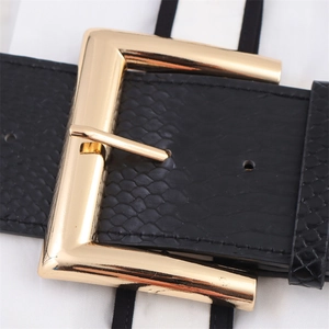 Detail view of a wide black faux leather belt with snake texture and large gold buckle