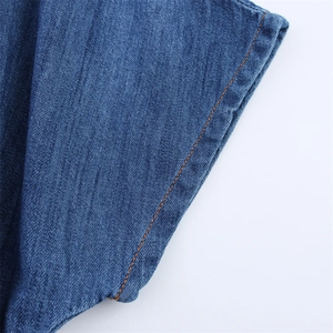 Detail of dark blue denim fabric showing orange double-stitching and twill texture