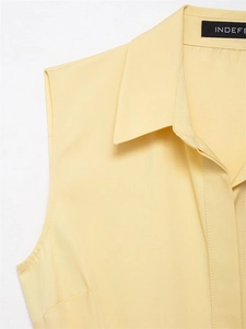 Close-up of the tailored collar and brand label on a pale yellow sleeveless shirt dress