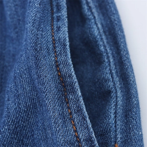 Detailed close-up of dark blue denim fabric with contrast stitching and pocket seams