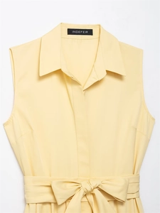 Detail view of pale yellow sleeveless shirt dress with belted bow waist and classic collar