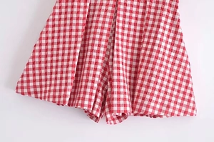 Detailed macro view of red gingham plaid textured fabric with vertical pleated folds