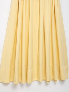 Detailed view of pale yellow pleated dress hemline in smooth chiffon fabric with drape