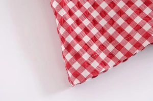 Macro shot of red gingham seersucker fabric detailing pleated texture and fine stitching