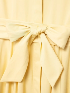 Detail shot of a light yellow shirt dress featuring a large decorative waist bow tie