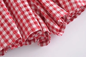 Close-up of red gingham seersucker fabric texture with pleated ruffle hem details