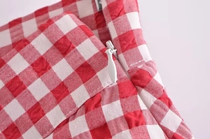 Close-up of invisible zipper detail on red gingham pleated shorts for women