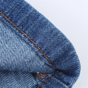 Detail of blue denim dress with orange contrast stitching and twill fabric texture