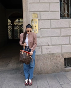 Outdoor street style view of a cropped dusty pink pilot jacket with large utility pockets