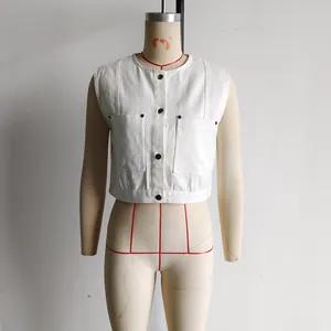 Detail of white sleeveless cropped denim vest with black buttons and utility chest pockets