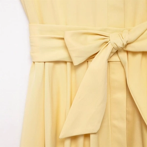 Pale yellow belted shirt dress featuring a structured waist bow and pleated details