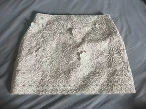 Macro shot of white floral lace mini skirt with intricate crochet patterns and scalloped edges
