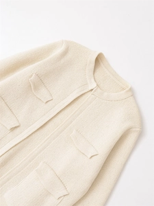 Gros plan d'un cardigan blanc crème en maille épaisse avec quatre poches décoratives