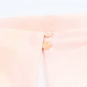 Macro view of peach pink satin dress with vertical shimmering shell buttons and twill texture