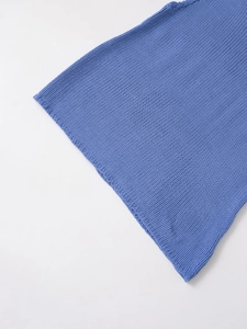 Macro shot of blue knit fabric texture and high-quality stitching on asymmetric top