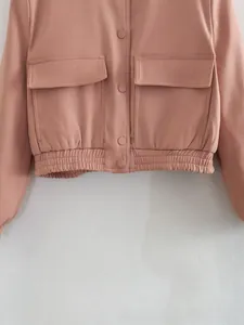 Detail view of pink-brown bomber jacket featuring large flap pockets and elastic hem